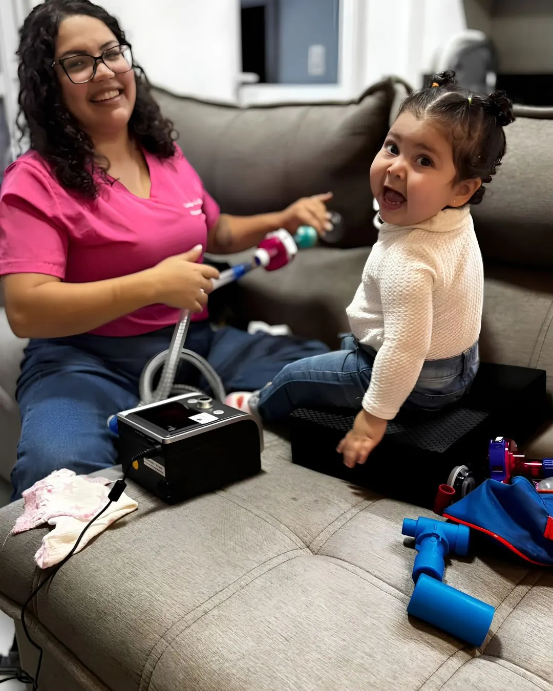Fisioterapeuta pediátrica sorrindo durante atendimento respiratório a uma criança.