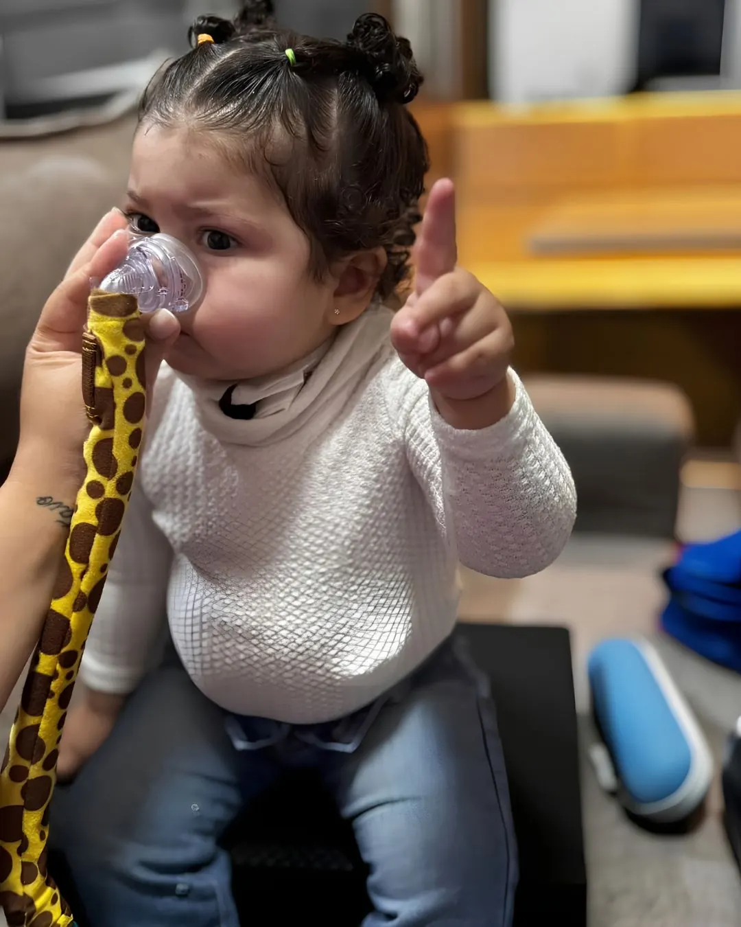 Criança segurando um brinquedo durante pausa no atendimento de fisioterapia respiratória.
