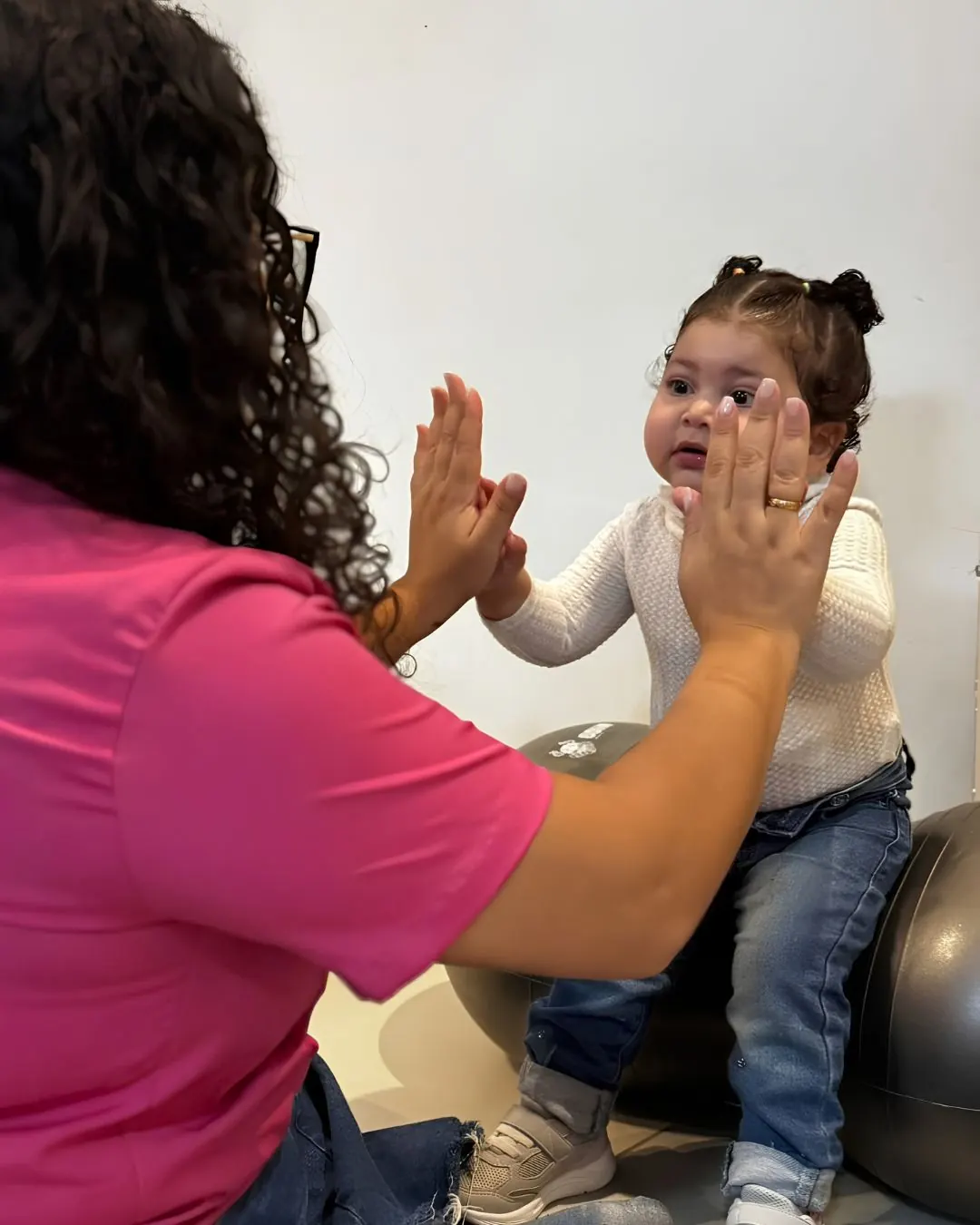 Fisioterapeuta e criança sorrindo ao final da sessão de fisioterapia domiciliar.